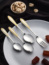 Four elegant stainless steel utensils with gold-plated handles on white plate, surrounded by mushrooms and chocolate pieces